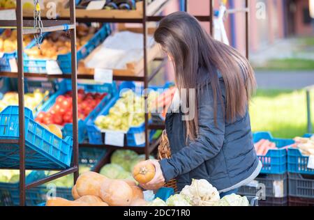 La femme de beauté choisit des légumes sur le marché des légumes Banque D'Images