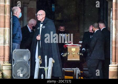 Le père Haydn England Simon porte une visière alors qu'il dirige le cercueil de Gladys Lewis de l'église pendant les funérailles de Gladys, Dean et Darren Lewis à l'église St Peter's Church à Pentre, au sud du pays de Galles. Mme Lewis et ses deux fils sont tous morts de Covid-19 dans les cinq jours. Banque D'Images