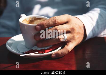 Gros plan d'une main d'homme tenant une tasse de café Banque D'Images