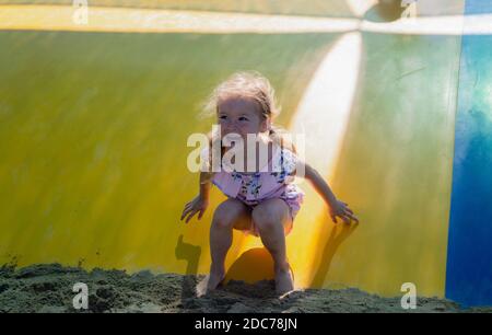 Petite fille blonde jouant dans le parc sautant sur un trampoline Banque D'Images