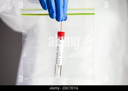 Kit d'échantillons d'auto-écouvillonnage pour la maladie du virus COVID-19, un scientifique de laboratoire médical tenant un sac en plastique contenant un tube à essai avec écouvillon pour la gorge ou le nez Banque D'Images