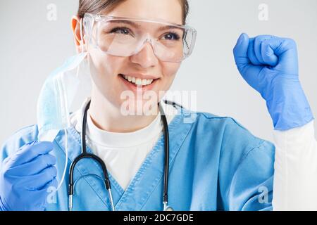 Médecin victorieux avec le poing serré et le bras relevé, célébrant sourire avec joie après que les patients ont réussi à vaincre la maladie virale et à se rétablir Banque D'Images