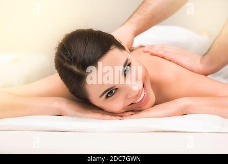 Femme de race mixte souriante lors d'un massage thérapeutique classique du dos dans un spa de bien-être Banque D'Images