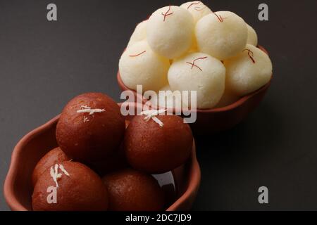 Célèbres desserts indiens rasgulla/ rosogulla/ roshogulla et gulab jamun/ gulabam servis dans un bol en terre. Banque D'Images