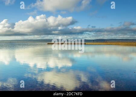 Réflexions sur l'eau et le ciel au lac marin West Kirby on Le Wirral avec vue sur les collines galloises Banque D'Images