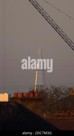 Wimbledon, Londres, Royaume-Uni. 19 novembre 2020. Le bord ouest du Shard capture la lumière du soleil en fin d'après-midi pendant un temps clair entre les nuages, encadré par une grue de construction et photographié à une distance de 10 miles. Crédit : Malcolm Park/Alay Live News Banque D'Images