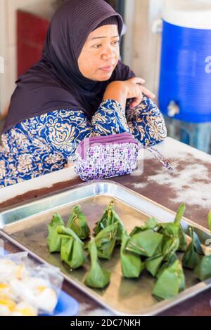 Une femme musulmane vendant des gâteaux de riz thaïlandais traditionnels enveloppés de feuilles de banane à Phuket, en Thaïlande Banque D'Images
