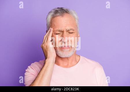 Gros plan portrait de son il beau attrayant mal déprimé épuisé homme fatigué aux cheveux gris touchant le temple se sentant mal isolé sur lumineux vif Banque D'Images