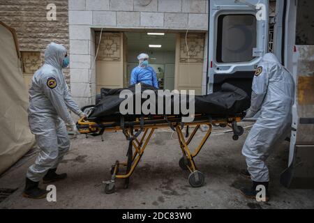 Idlib City, Syrie. 19 novembre 2020. Des membres spécialisés de la Défense civile syrienne, également connus sous le nom de casques blancs, emportent le corps d'un homme qui sera enterré après sa mort suite à la sous-traitance de la COVID-19, en raison d'une augmentation du nombre de décès liés au coronavirus dans le nord-ouest de la Syrie. Credit: Aras Alkharboutli/dpa/Alamy Live News Banque D'Images