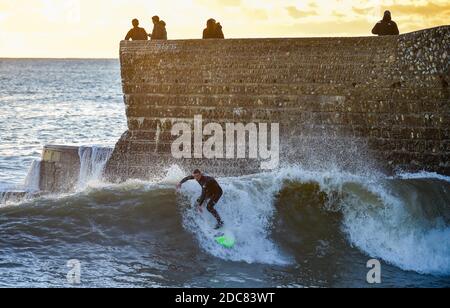 Brighton Royaume-Uni 19 novembre 2020 - UN surfeur attrape une vague au coucher du soleil au large de Brighton Beach tandis que les gens apprécient la fin de la journée le long de la côte sud : Credit Simon Dack / Alay Live News Banque D'Images