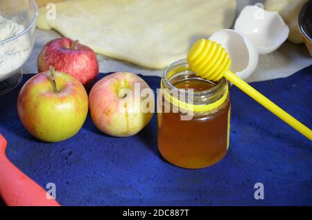 Divers ingrédients pour la cuisson de saison d'hiver et d'autres recettes, miel, pommes, herbes et épices sur un fond bleu foncé. Vue de dessus. Banque D'Images