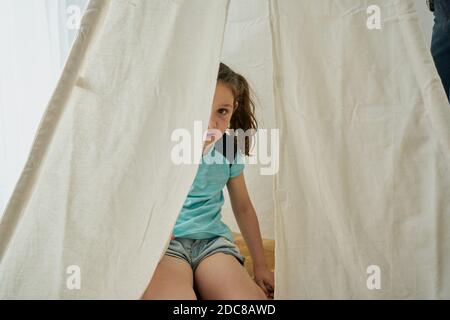 fille regardant dans une tente blanche de tipi à l'intérieur de leur maison. concept de maison Banque D'Images