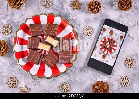 Concept pour la photographie de nourriture avec des pralines de gâteau d'hiver superposées allemandes Appelé « Baumkuchen » sur la plaque à côté du téléphone portable avec photo prise de nourriture Banque D'Images