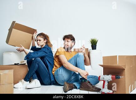 homme et femme assis sur le sol avec leur dos à d'autres travaux de rénovation déplacer une fleur dans un pot Banque D'Images