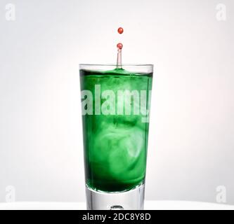 Une goutte de colorant colorée flotte dans un verre d'eau transparent Banque D'Images