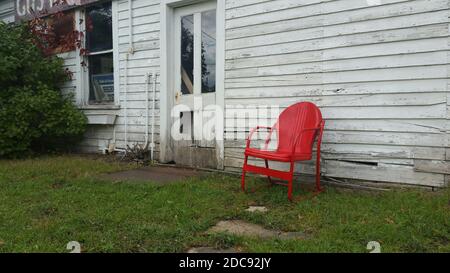 chaise rouge vintage vide contre les intempéries et le vieux bâtiment en bois extérieur Banque D'Images