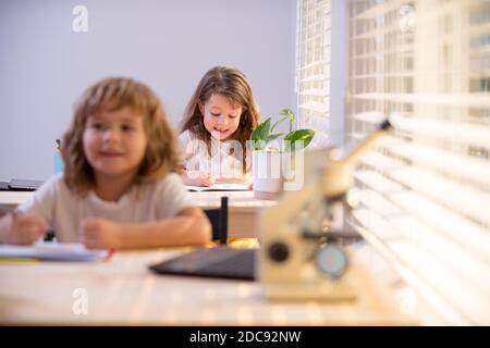 Enfants assis au bureau dans la salle de classe et test d'écriture. Les élèves écrivent dans un carnet pendant la leçon en classe. Banque D'Images