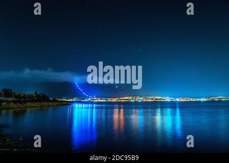 Petite station balnéaire de Gelendzhik avec des montagnes et l'éclairage de nuit se reflète dans l'eau de la baie de mer et ciel nocturne lumineux avec des étoiles. Gelendzhik - de grandes lettres sur les montagnes sur la langue russe Banque D'Images