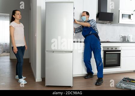 Réfrigérateur Handyman Service dans le masque facial. Réfrigérateur cassé Banque D'Images