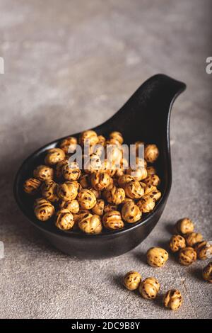 Pois chiches jaunes rôtis dans un bol noir sur fond de pierre (nom turc; sari leblebi). Banque D'Images