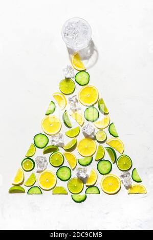 Motif coloré composé de tranches d'agrumes citron, citron vert et concombre. Décorer le concept de gin comme arbre de Noël avec des cubes de glace et un verre de gin sur W Banque D'Images