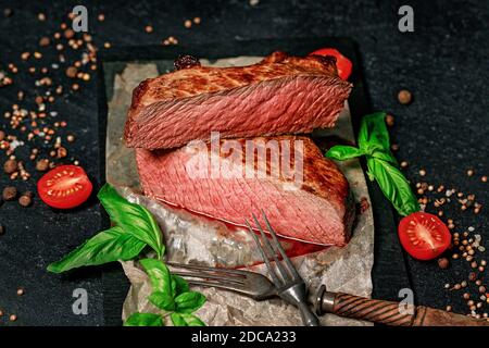 Steak de bœuf rare. Épices et herbes sur fond sombre. Viande juteuse et appétissante. Banque D'Images