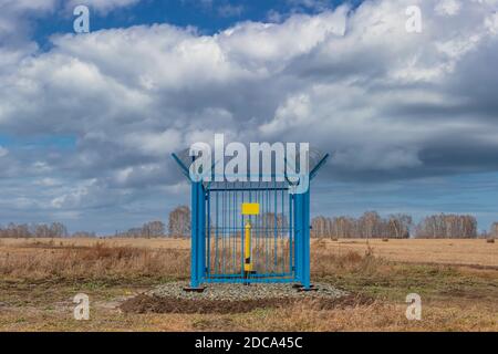 Photo d'une station de gaz industriel en cage avec barbelés sur le dessus de la clôture. Tuyau de gaz jaune au milieu de la cage, plaque jaune vide sur la clôture. Banque D'Images