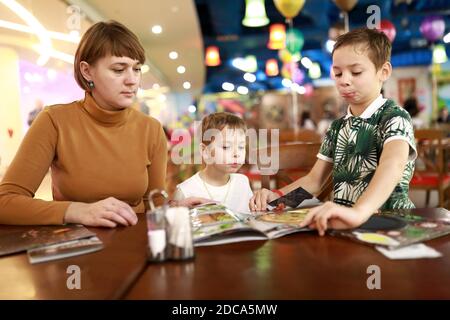 Mère avec ses fils qui choisit un plat au menu dans le restaurant Banque D'Images