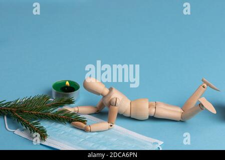Mannequin en bois, masque médical, bougie et branche de sapin. Concept d'isolement. Banque D'Images