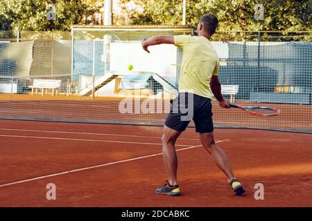 Vue arrière d'un homme jouant au tennis sur un court de tennis Banque D'Images