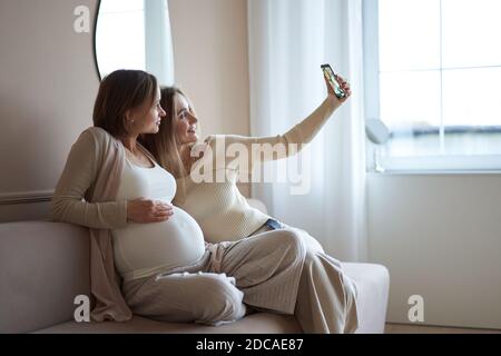 filles multiethniques et femme enceinte heureuse prenant selfie sur smartphone . Photo de haute qualité. Banque D'Images