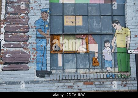 MORGANTOWN, ÉTATS-UNIS - 17 juin 2020: Dessin mural de policiers aidant la famille avec fenêtre sur le mur cassé Banque D'Images