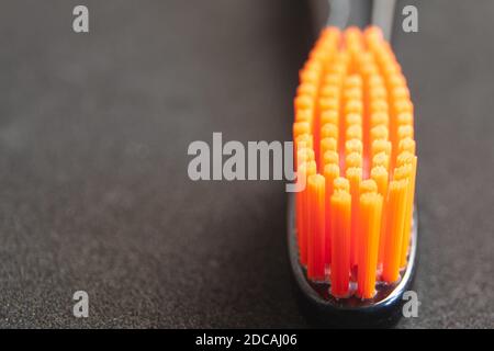 Brosse à dents à tête noire avec poils orange gros plan sur le noir arrière-plan Banque D'Images