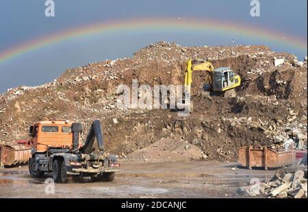 Pelle hydraulique en décharge sur fond arc-en-ciel. Camion à benne basculante avec réservoir métallique et capacité pour le stockage et le transport des déchets au MSW. Mise au rebut de CO Banque D'Images