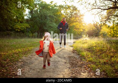 En cours d'exécution. Père heureux et petite fille mignonne marchant sur le chemin de la forêt en automne ensoleillé jour. Temps de famille, togethterness, parent et concept d'enfance heureuse. Week-end avec des émotions sincères. Banque D'Images