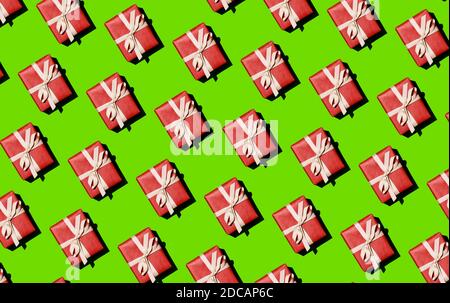 Cadeaux de Noël rouges attachés avec un ruban blanc sur un fond vert. Fond de fête, motif Banque D'Images