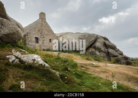 Maison entre rochers à Meneham, sur la côte atlantique dans le nord de la Bretagne (France), jour nuageux en été Banque D'Images