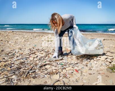 Une jeune femme nettoie la plage à partir de bouteilles en plastique Banque D'Images