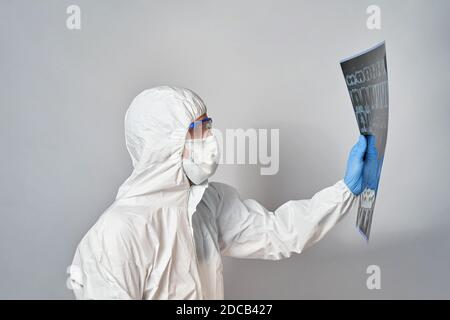 un médecin dans un costume de protection et un masque regarde Les résultats d'une acquisition CT des poumons Banque D'Images