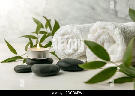 pierres de spa avec serviettes blanches, bougie en feu et plante verte Banque D'Images