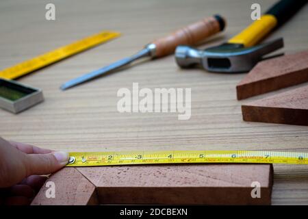 Gros plan sur les mains d'une femme mesurant une planche en bois avec un mètre ruban avec un ensemble d'outils manuels de travail pour le bois, Toolset avec t Banque D'Images
