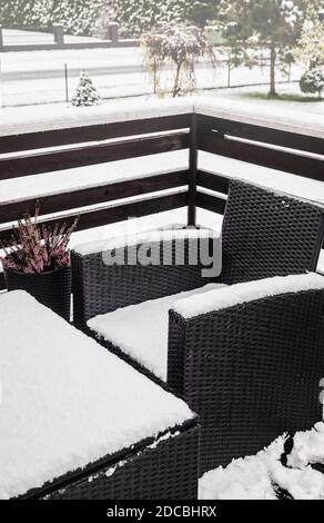 Vue rapprochée sur le rotin en plastique synthétique enneigé et les meubles de jardin en verre par temps froid d'hiver. Concept d'entretien des meubles de jardin. Banque D'Images