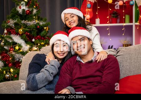 Portrait de famille heureuse, père mère et fille, célébrer Noël dans la salle de séjour, saison des fêtes Banque D'Images