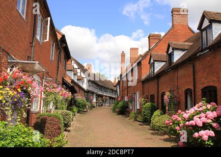 Maisons en briques et à colombages dans le pays de Shakespeare, Malt Mill Lane Alcester Warwickshire, Royaume-Uni. Avec paniers suspendus et fleurs en été. Banque D'Images