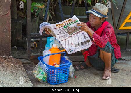 La vie quotidienne au Myanmar - un jeune homme lisant des journaux à Yangon, Myanmar (Birmanie), en Asie, en février Banque D'Images