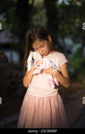 Triste bouleversé caucasienne fille embrassant jouet. L'enfant s'étreinte d'un ours en peluche dans le parc à l'extérieur. Enfant solitaire perdu dehors. Les problèmes d'enfance malheureux sont les plus graves Banque D'Images