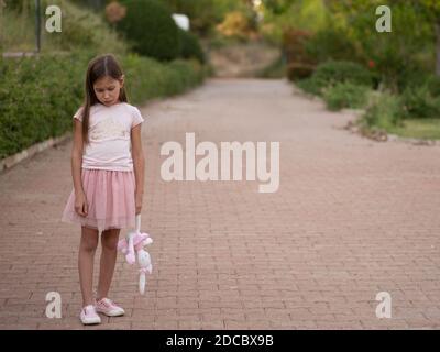 Triste fille embrassant le ours en peluche tristesse seule dans le parc de jardin vert. Solitaire fille se sentant triste malheureux marche à l'extérieur avec le meilleur jouet ami. Autisme enfant pl Banque D'Images