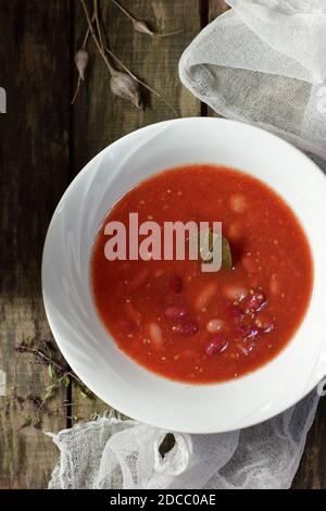 Repas aux protéines végétaliennes avec haricots rouges et sauce tomate dans un bol blanc plat sur une table rustique, au-dessus de la vue de dessus, concept végétarien Banque D'Images