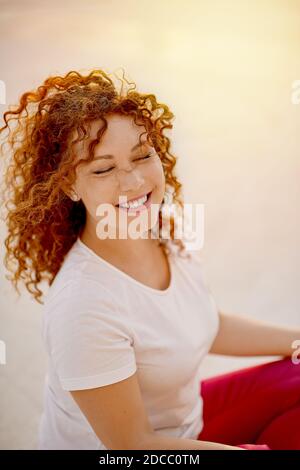 Jeune femme à tête rouge assise dans une posture de yoga Banque D'Images