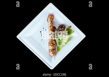 Poulet kebab sur un bâton doué avec des herbes sur une assiette. Banque D'Images